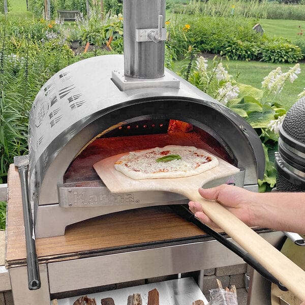 WPPO Karma 25 Inch Stainless Steel Wood Fired Countertop Pizza Oven person placing pizza into oven